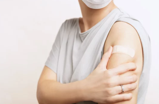 Person gently touching a mild sore spot on their arm after a B12 injection at home