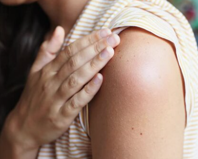 Person checking a mild red spot after a B12 injection site reaction on the upper arm