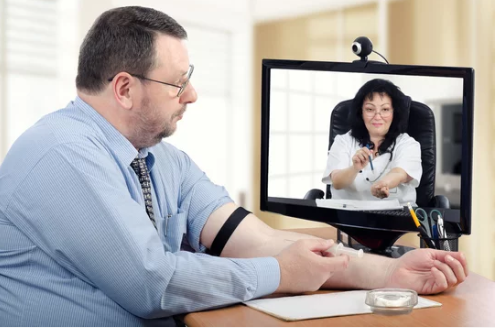 Adult preparing a B12 injection kit at home while following telehealth guidance on a laptop